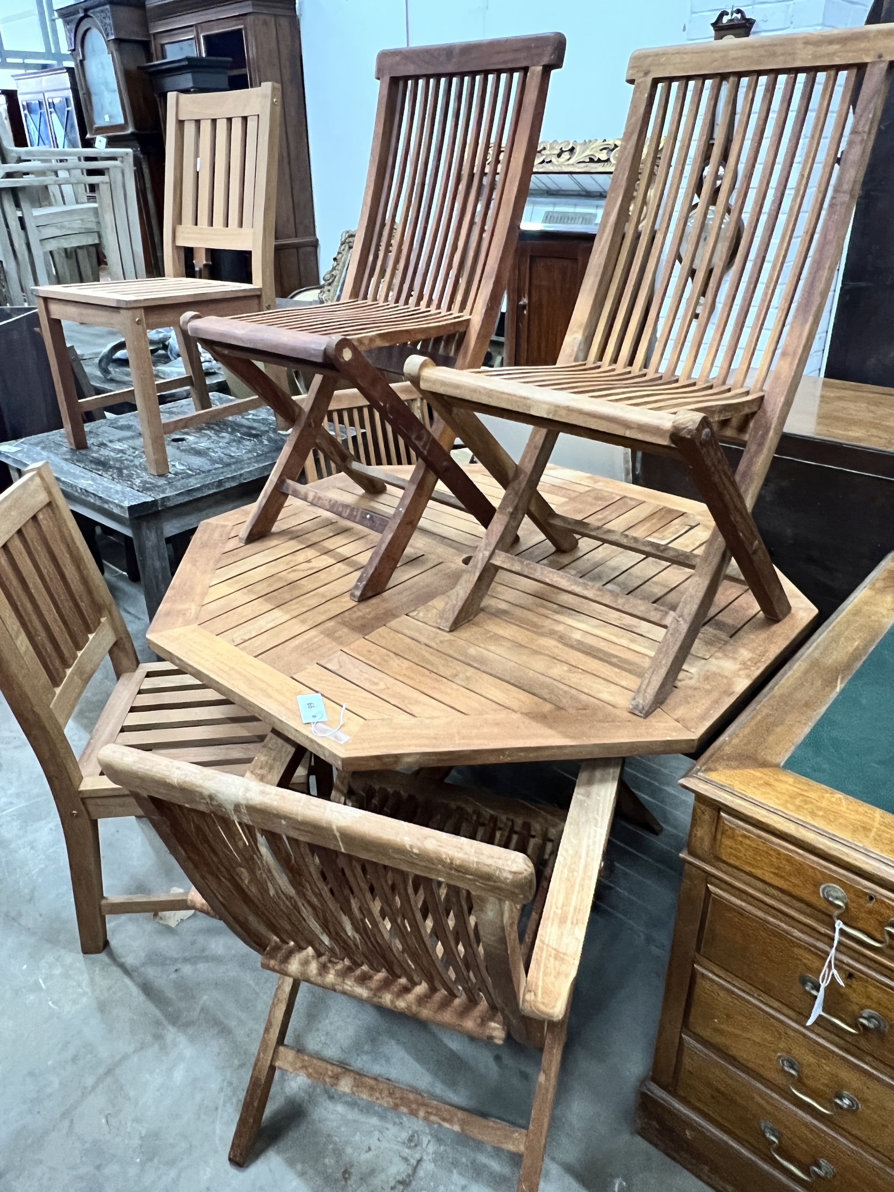 An octagonal teak folding garden table, length 120cm, height 74cm and four folding teak garden chairs, two with arms